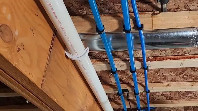 Blue PEX supply lines running along wood joists above a white drain pipe