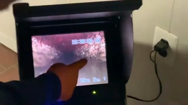 Hand pointing at a plug-in camera monitor showing red-tinted footage of the inside of a pipe