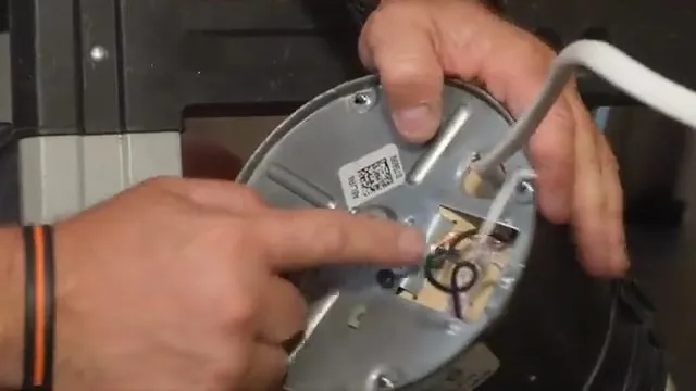 Hand pointing at the bottom plate of a garbage disposal while another hand holds the unit
