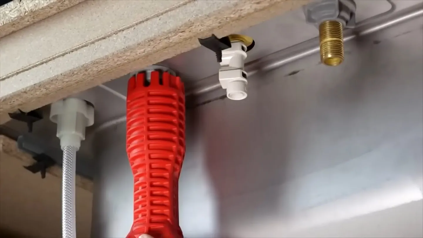 Red multi-socket sink tool fitted up under a sink beside white supply fittings