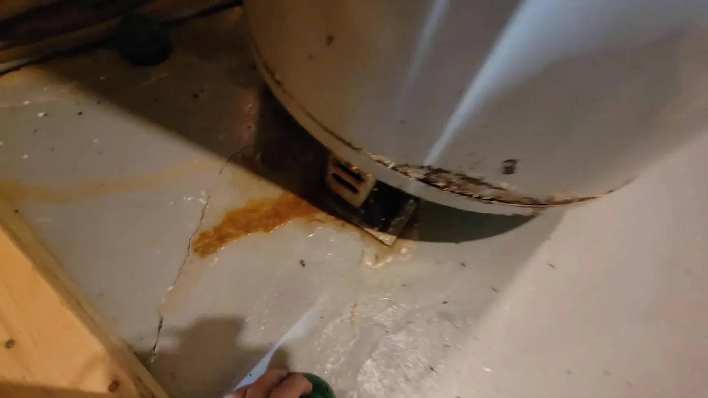 Rust-colored staining on the floor around the base of a tank water heater