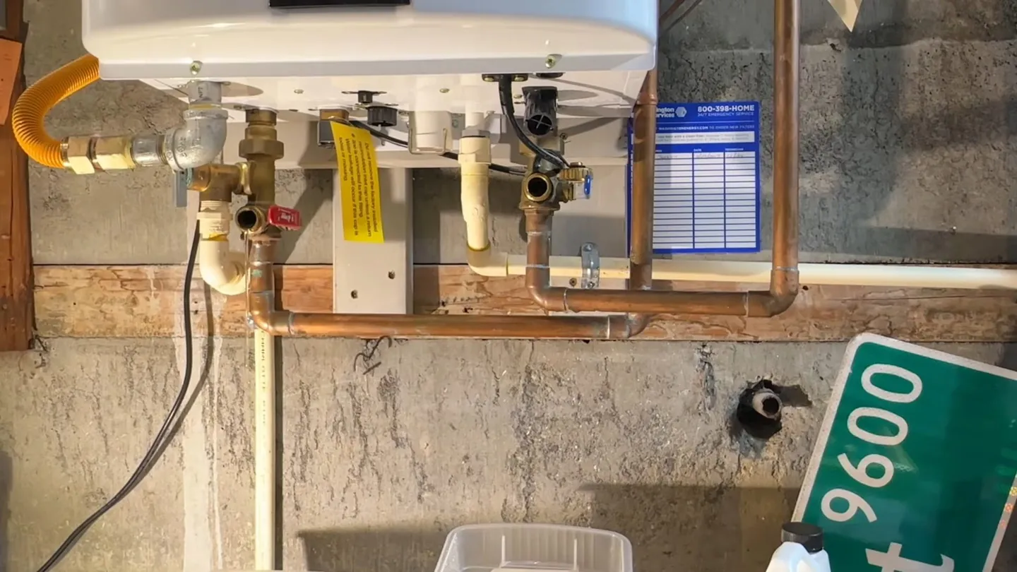 Underside of a tankless water heater showing a gas line, copper water pipes and service valves