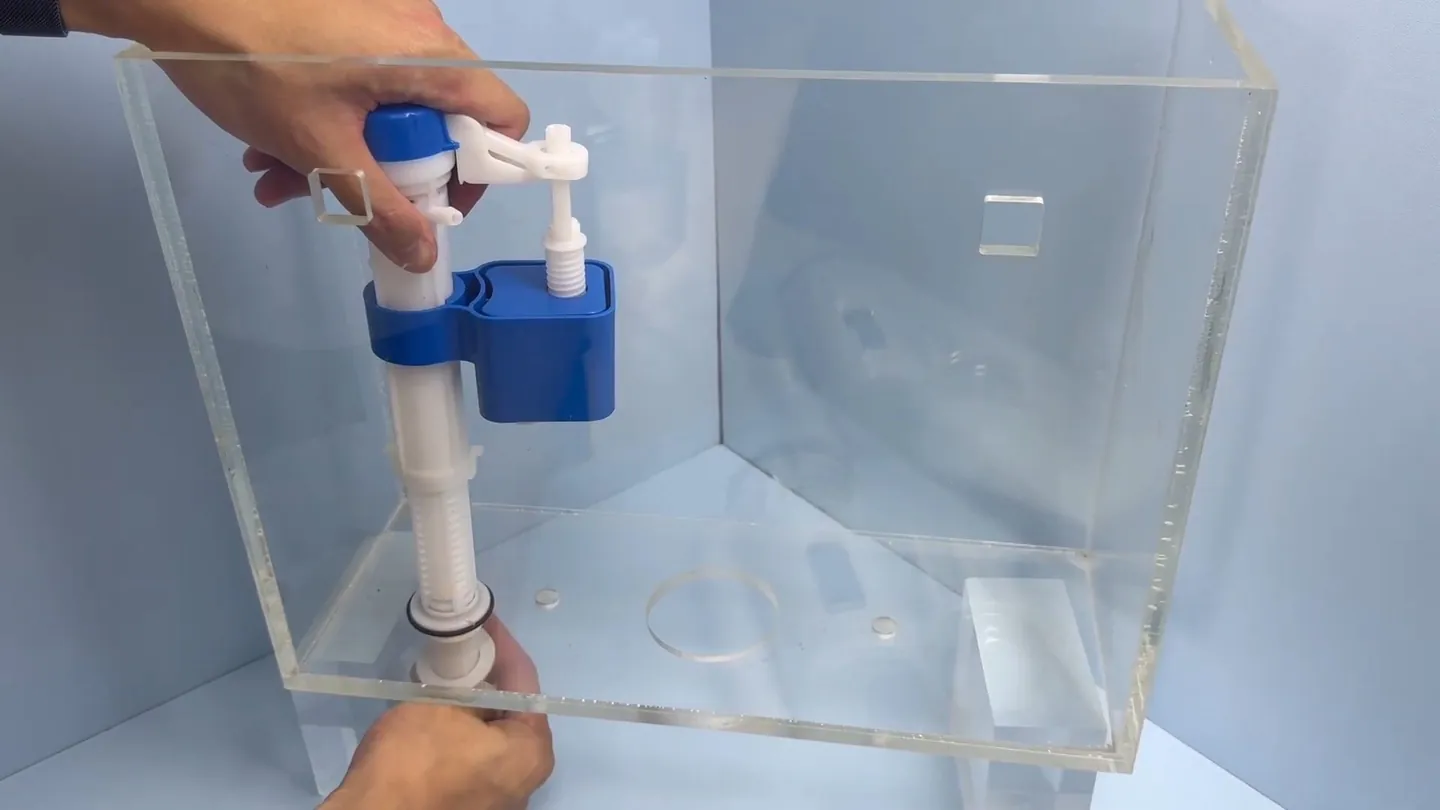 Hands adjusting a blue and white fill valve inside a clear acrylic tank